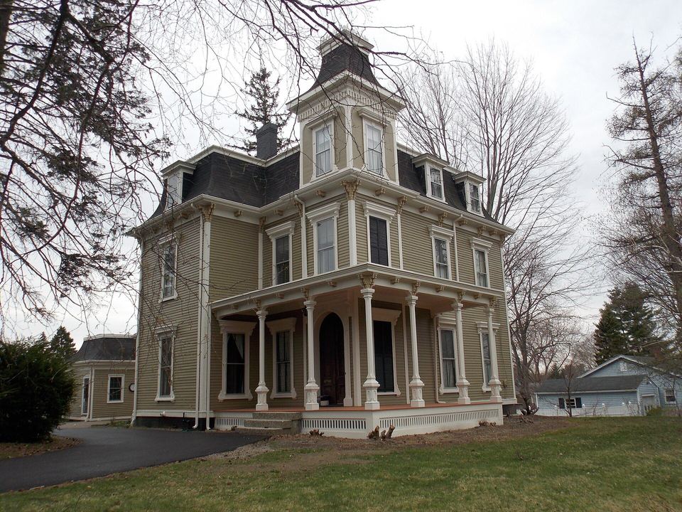 Victorian clapboard house with a mansard roof, bracketed eaves and a columned front porch