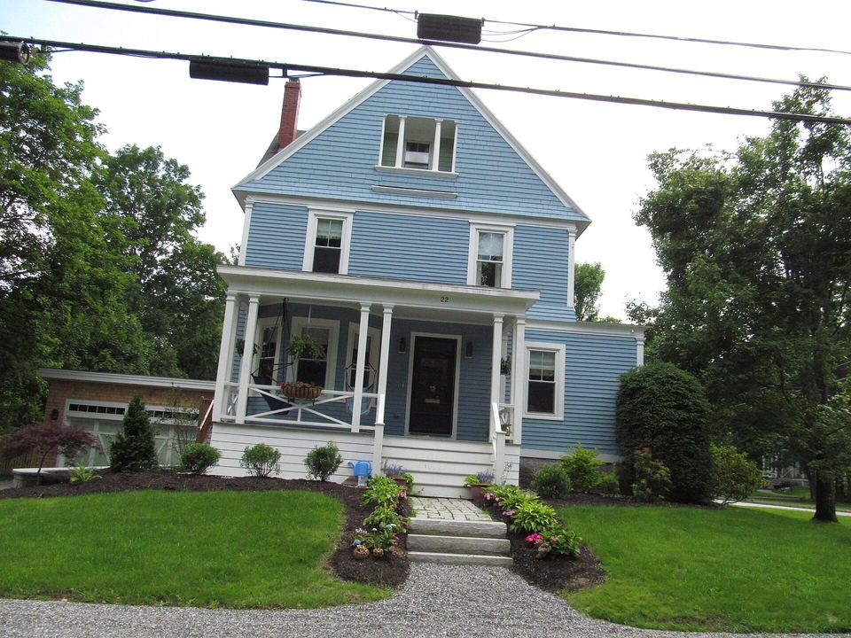 Blue clapboard house with a front gable, a covered porch and a green lawn