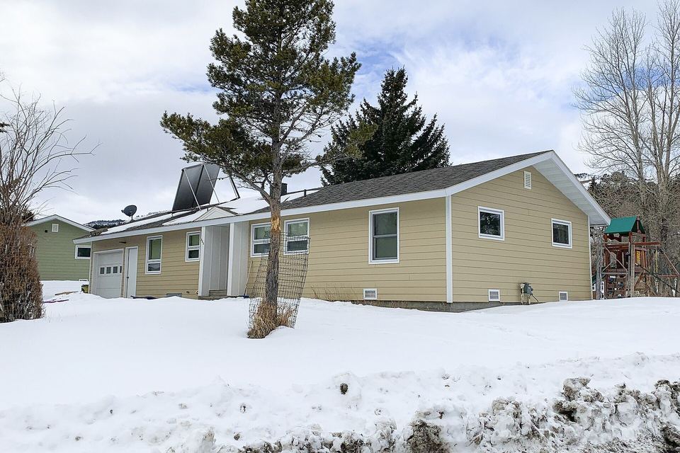 Single-story house with new tan lap siding and white trim beside deep snow