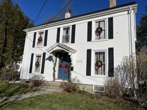 White clapboard house with black shutters and wreaths in the double-hung windows